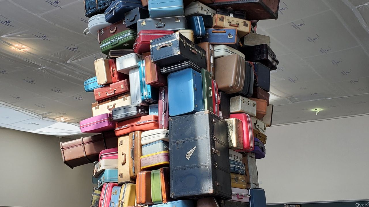 A tall stack of suitcases on a pallet inside an airport terminal